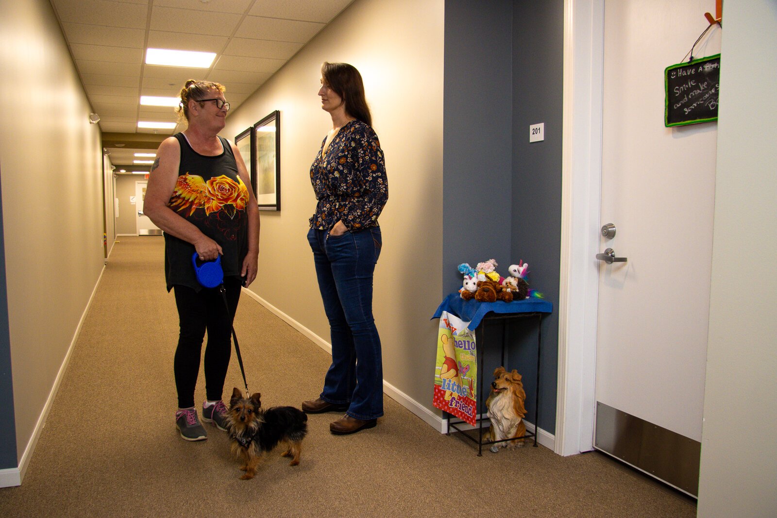 Resident Teresa Brant, her dog, Jack, and Kittie Tuinstra catch up in the hallway at Shelby Trails Apartments.