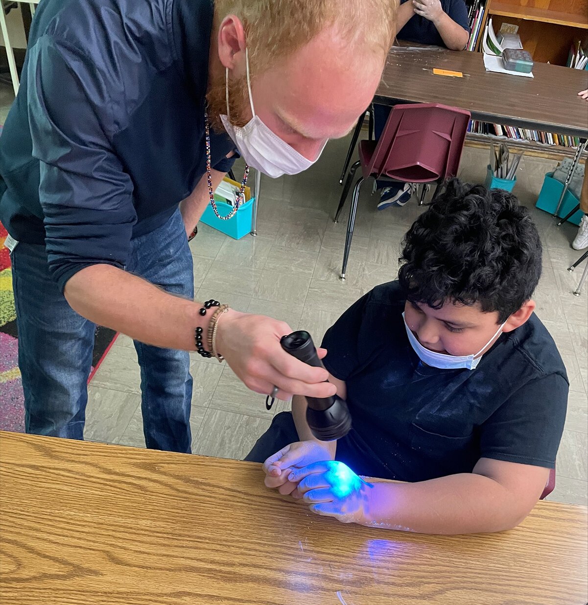 Third-grade students at Neinas Dual Language Learning Academy learning about the importance of proper hand washing and experimenting with glowing germs.