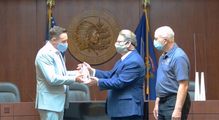Greater Ottawa County United Way President Patrick Moran presents County Administrator Al Vanderberg and County Commission Chair Roger Bergman with the G.W. Haworth Strength of the Community Award.