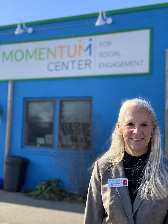 Barbara Lee VanHorssen stands in front of the Momentum Center for Social Engagement.