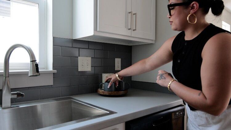 A woman tidies the kitchen counter in a staged CLT home at 2080 Union.