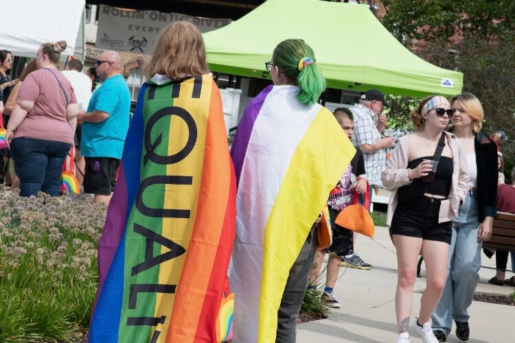 An attendee is wrapped in a Pride flag at at Allegan, Speak Up event.