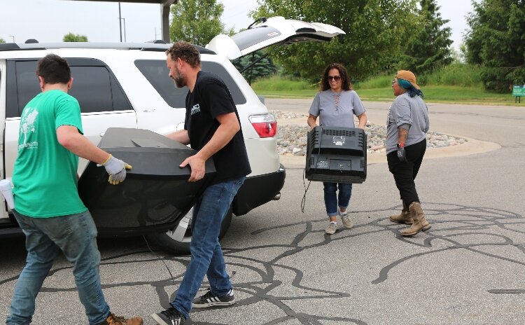 Gentex employees unload two TVs during the company's annual electronics recycling event.