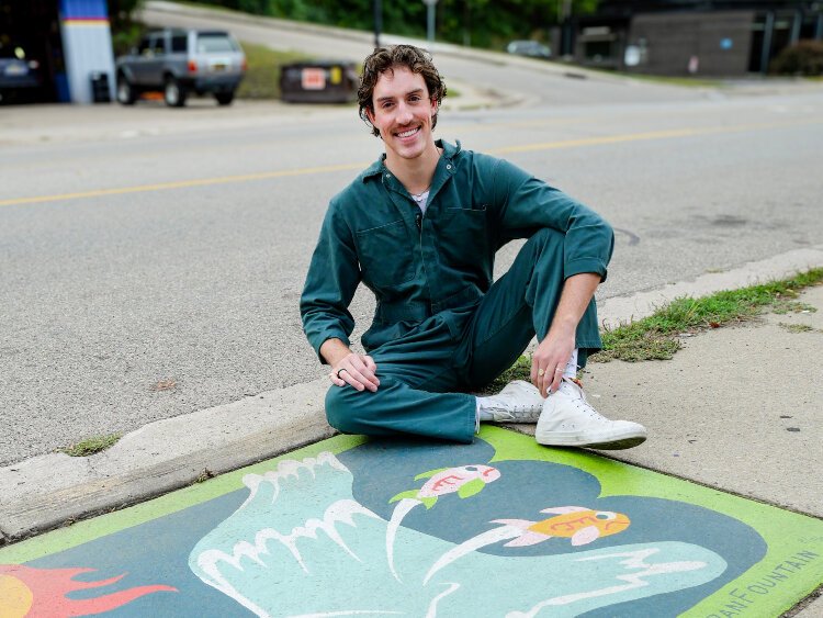 Jarran Fountain proudly poses with one of the street drain art pieces he created for Creston.