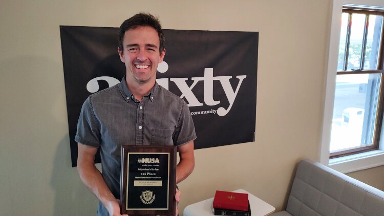 Jake Norris, executive director of 3Sixty, poses with the neighborhood nonprofit's award for neighborhood of the year.