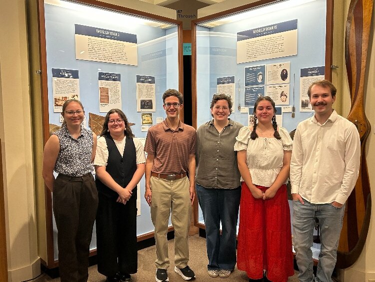 Holland Museum summer interns pose in front of a newly installed military service display, completed as their group summer project.